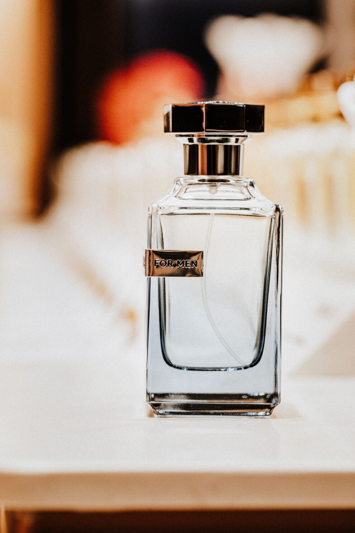 Elegant men's cologne bottle labeled "For Men" with warm amber bokeh light in the background